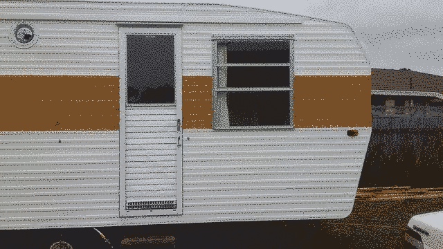 The right hand half of the caravan. A single door is near the middle of the shot, with our bedroom window to the right. The sky is overcast and a thick band of mustard is painted across the middle of an otherwise white caravan