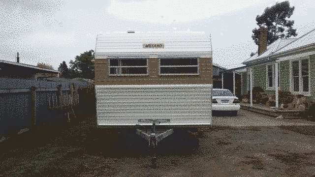 The towing end of the caravan, showing two narrow windows and the millard logo.