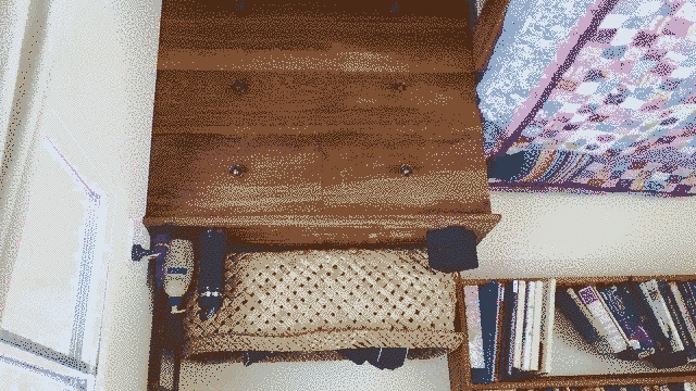 Dresser with wahakura on top. Rich warm brown rimu wood. to the left is a bookshelf and a blue/pink quilt on the bed.