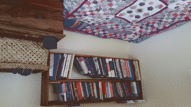 Two shelf bookshelf, dresser and wahakura on right with double bed center left. the shelves are full of books.